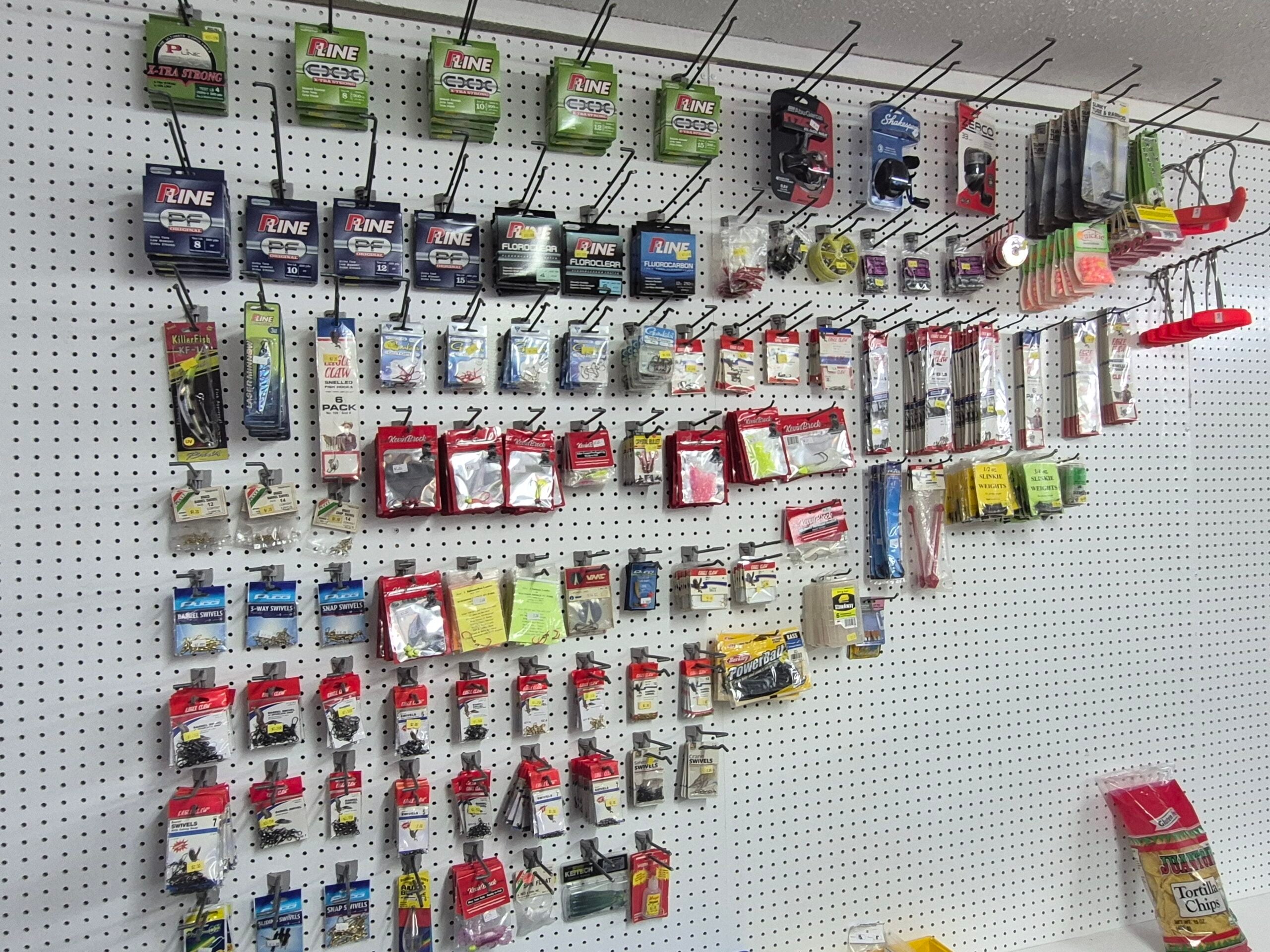 A pegboard wall displays various fishing supplies, including fishing lines, hooks, lures, bobbers, and other tackle in plastic packaging, all neatly arranged for sale.