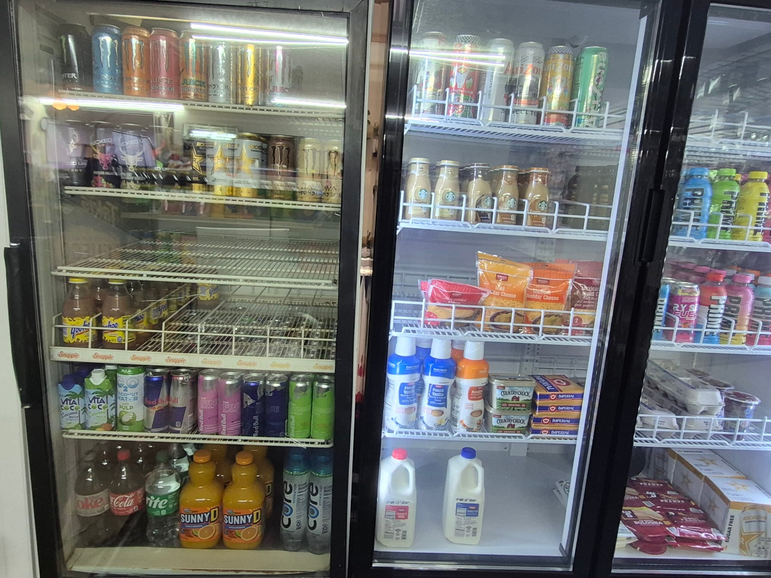 A refrigerated display with canned drinks, bottled juices, and smoothies on the left, and various dairy products including milk, cream, and eggs on the right, along with packs of butter and yogurt on wire shelves.